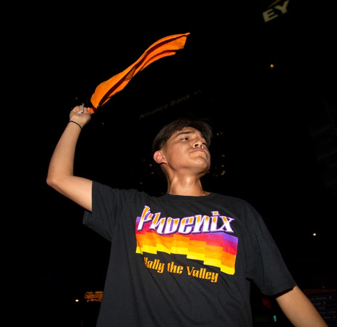 Jaden Chester waives a towel in the air to celebrate after the Suns beat the  Milwaukee Bucks 118-108 in Game 2 of the NBA Finals outside the Phoenix Suns Arena in Phoenix on July 8, 2021.