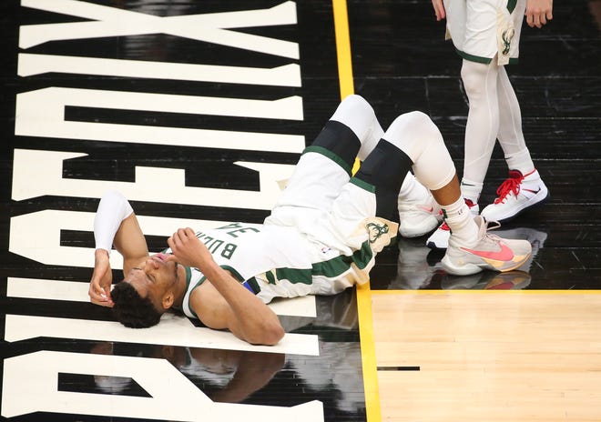 Milwaukee Bucks forward Giannis Antetokounmpo (34) lays on the ground after a foul by Phoenix Suns guard Cameron Payne during Game 2 of the NBA Finals at Phoenix Suns Arena July 8, 2021.