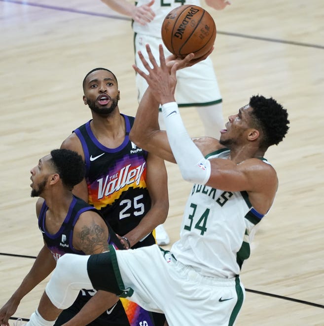 Milwaukee Bucks forward Giannis Antetokounmpo (34) shoots over Phoenix Suns forward Mikal Bridges (25) and Phoenix Suns guard Cameron Payne (15) during the first quarter of Game 5 of the NBA Finals at Footprint Center in Phoenix on Saturday.