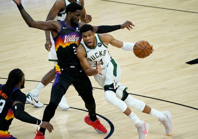 Milwaukee Bucks forward Giannis Antetokounmpo (34) drives against Phoenix Suns center Deandre Ayton (22) during the first quarter of Game 5 of the NBA Finals at Footprint Center in Phoenix on Saturday.