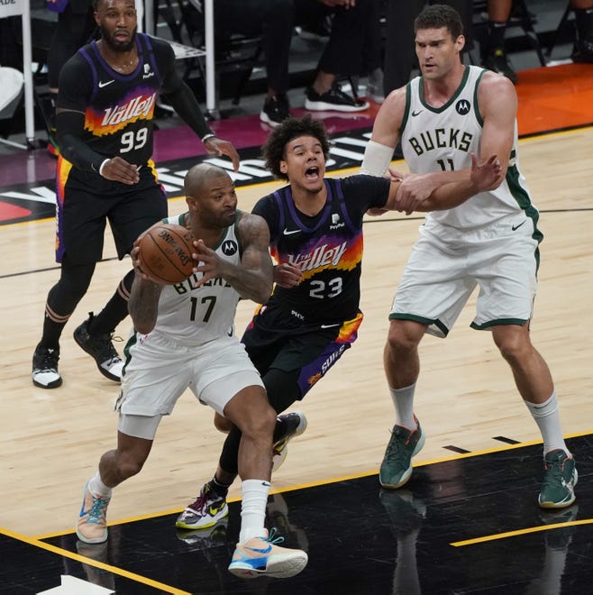 Phoenix Suns forward Cameron Johnson (23) cries foul as heÕs fouled by Milwaukee Bucks center Brook Lopez (11) as Milwaukee Bucks forward P.J. Tucker (17) drives with the ball during the second quarter of Game 5 of the NBA Finals at Footprint Center in Phoenix on Saturday.