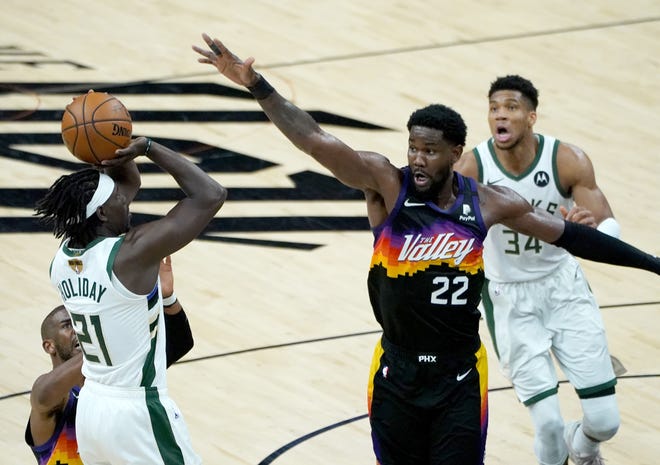Milwaukee Bucks guard Jrue Holiday (21) shoots a 3-point shot guarded by Phoenix Suns center Deandre Ayton (22) during the third quarter of Game 5 of the NBA Finals at Footprint Center in Phoenix on Saturday.