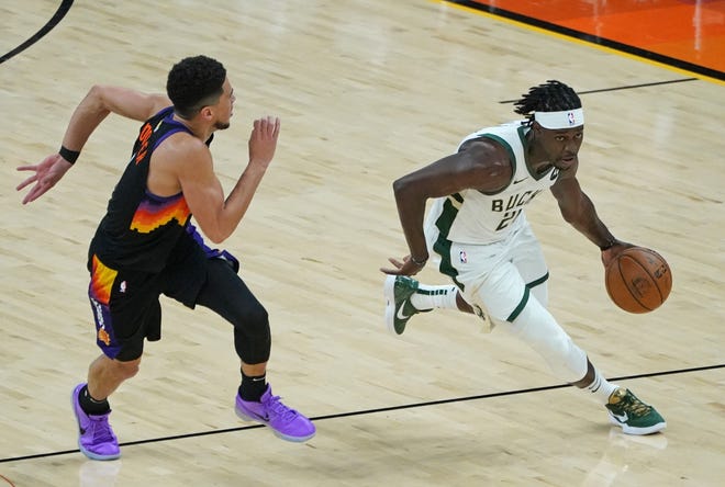 Milwaukee Bucks guard Jrue Holiday (21) steals the ball from Phoenix Suns guard Devin Booker (1) during the third quarter of Game 5 of the NBA Finals at Footprint Center in Phoenix on Saturday.