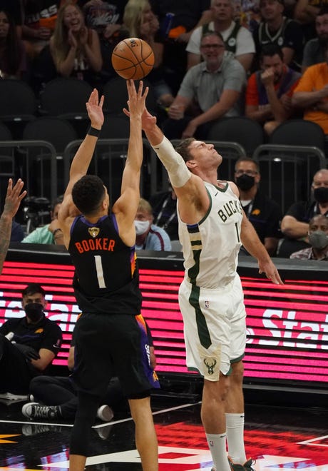 Milwaukee Bucks center Brook Lopez (11) tries to block a shot by Phoenix Suns guard Devin Booker (1) during the second quarter of Game 5 of the NBA Finals at Footprint Center in Phoenix on Saturday.