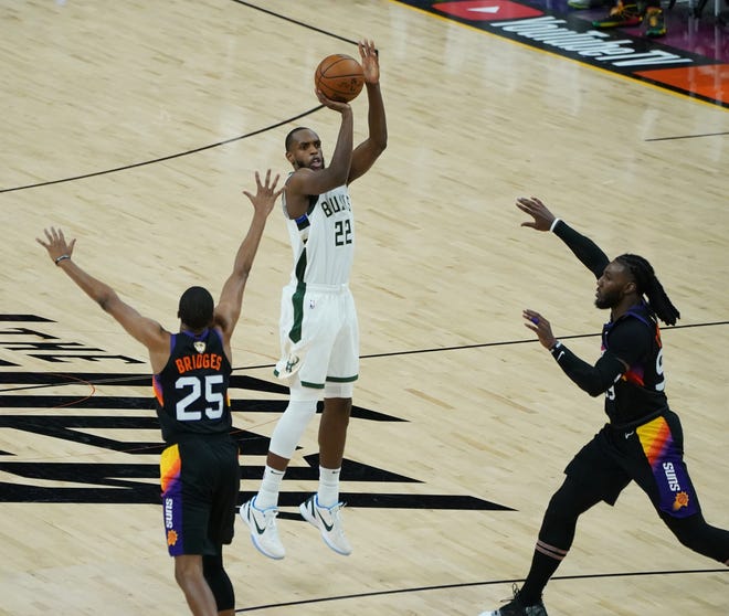 Milwaukee Bucks forward Khris Middleton (22) hits a 3 guarded by Phoenix Suns forward Mikal Bridges (25) and Phoenix Suns forward Jae Crowder (99) during the third quarter of Game 5 of the NBA Finals at Footprint Center in Phoenix on Saturday.