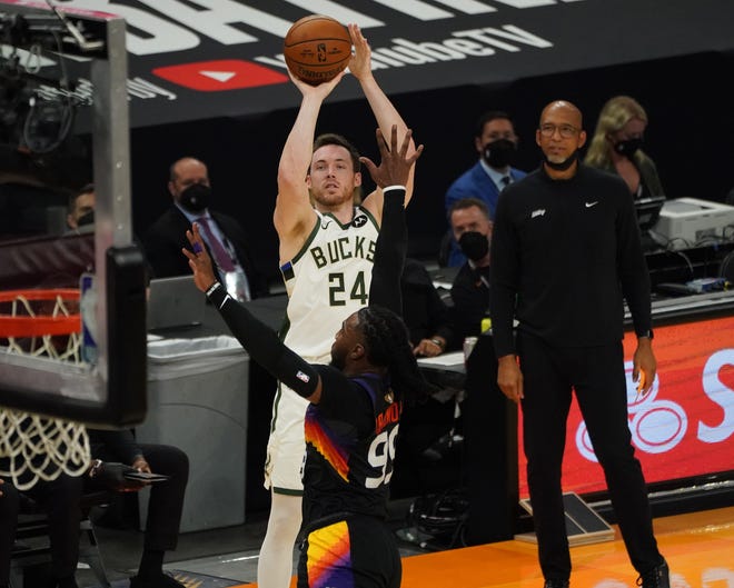 Milwaukee Bucks guard Pat Connaughton (24) shoots a 3-point shot over Phoenix Suns forward Jae Crowder (99) during the second quarter of Game 5 of the NBA Finals at Footprint Center in Phoenix on Saturday.