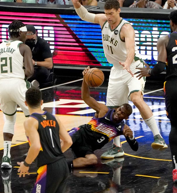 Phoenix Suns guard Chris Paul (3) falls to the floor guarded by Milwaukee Bucks center Brook Lopez (11) during the first quarter of Game 5 of the NBA Finals at Footprint Center in Phoenix on Saturday.