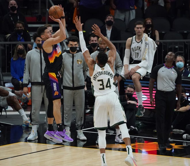 Phoenix Suns guard Devin Booker (1) hits a 3-point shot over Milwaukee Bucks forward Giannis Antetokounmpo (34) during the first quarter of Game 5 of the NBA Finals at Footprint Center in Phoenix on Saturday.