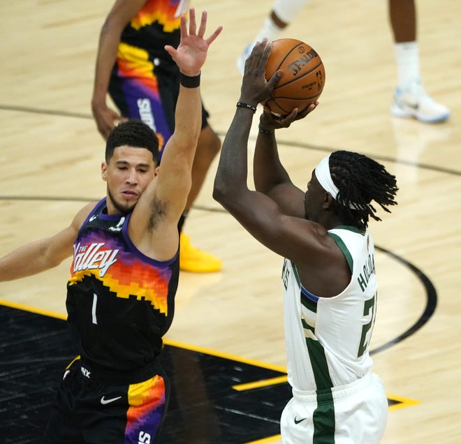 Milwaukee Bucks guard Jrue Holiday (21) shoots over Phoenix Suns guard Devin Booker (1) during the first quarter of Game 5 of the NBA Finals at Footprint Center in Phoenix on Saturday.