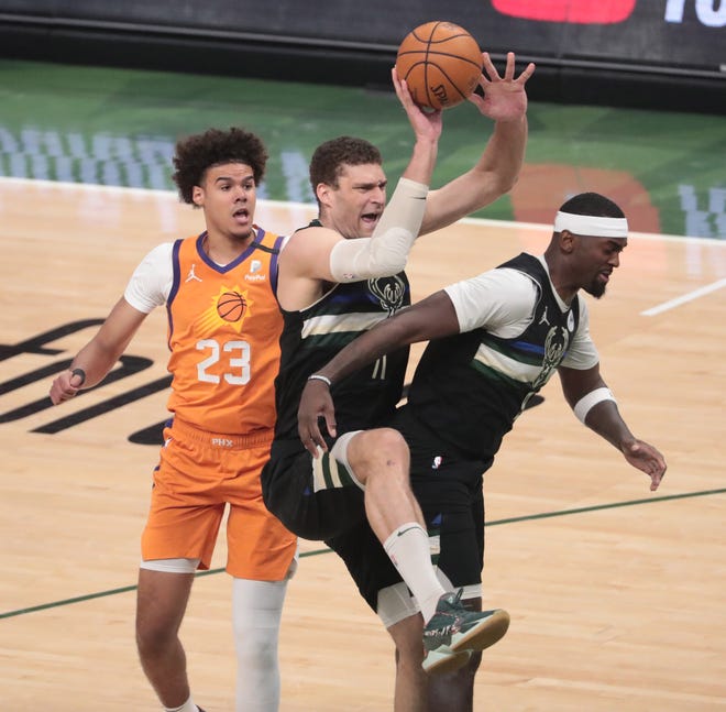 Milwaukee Bucks center Brook Lopez (11) grabs a rebound between Phoenix Suns forward Cameron Johnson (23) and Bucks guard Jrue Holiday (21) during Game 6 of the NBA Finals at Fiserv Forum July 20, 2021.
