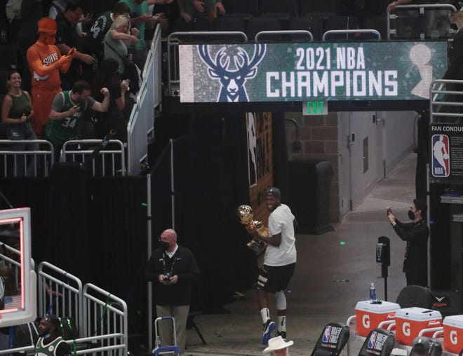 Milwaukee Bucks forward Khris Middleton (22) walks with the Larry O'Brien Championship Trophy after beating the Phoenix Suns in Game 6 of the NBA Finals at Fiserv Forum July 20, 2021.