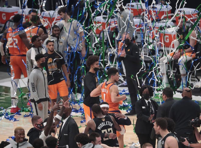 Confetti falls down on Phoenix Suns guard Devin Booker (1) as Milwaukee Bucks players celebrate after winning Game 6 of the NBA Finals at Fiserv Forum July 20, 2021.