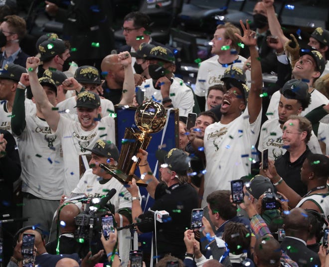 Milwaukee Bucks head coach Mike Budenholzer and his players celebrate with the Larry O'Brien Championship Trophy after beating the Phoenix Suns in Game 6 of the NBA Finals at Fiserv Forum on July 20, 2021.