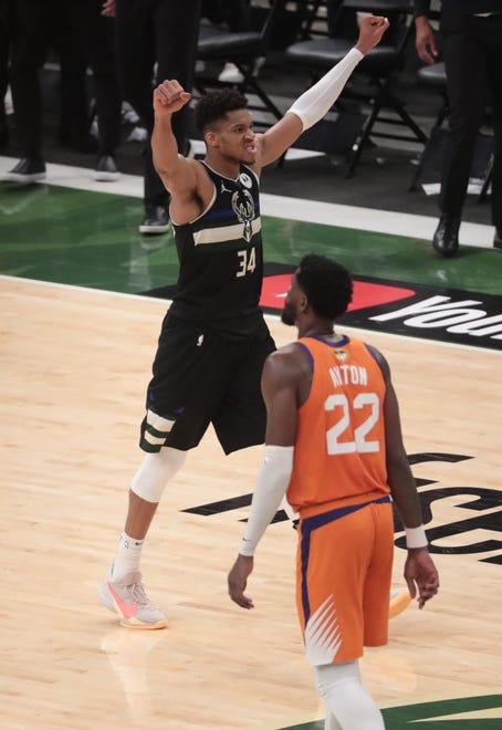 Milwaukee Bucks forward Giannis Antetokounmpo (34) raises his arms in front of Phoenix Suns center Deandre Ayton (22) after winning Game 6 of the NBA Finals at Fiserv Forum July 20, 2021.