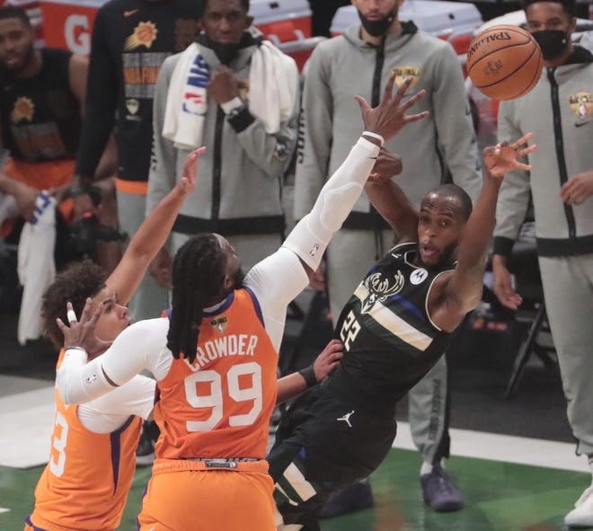 Milwaukee Bucks forward Khris Middleton (22) passes while defended by Phoenix Suns forwards Cameron Johnson (23) and Jae Crowder (99) during Game 6 of the NBA Finals at Fiserv Forum July 20, 2021.