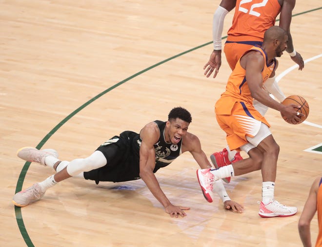 Milwaukee Bucks forward Giannis Antetokounmpo (34) falls over a screen by Phoenix Suns center Deandre Ayton (22) while defending guard Chris Paul (3) during Game 6 of the NBA Finals at Fiserv Forum July 20, 2021.