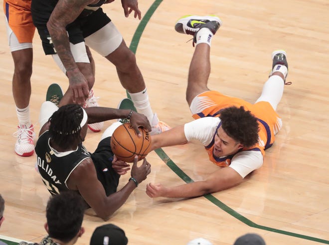 Phoenix Suns forward Cameron Johnson (23) scrabbles for a loose ball with Milwaukee Bucks guard Jrue Holiday (21) during Game 6 of the NBA Finals at Fiserv Forum July 20, 2021.