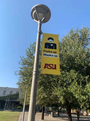 Un cartel que dice "Forks up. Máscaras arriba" se muestra en el campus de la Universidad Estatal de Arizona en el centro de Phoenix el 5 de agosto. El propósito del cartel es animar a los estudiantes a protegerse a sí mismos y a los demás del COVID-19.