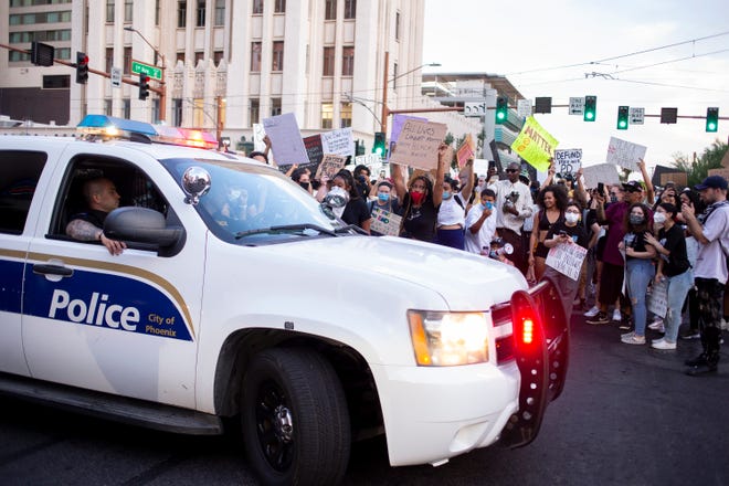Protesters hold up signs in front of a Phoenix police patrol car during a march against police brutality on June 4, 2020, in downtown Phoenix.