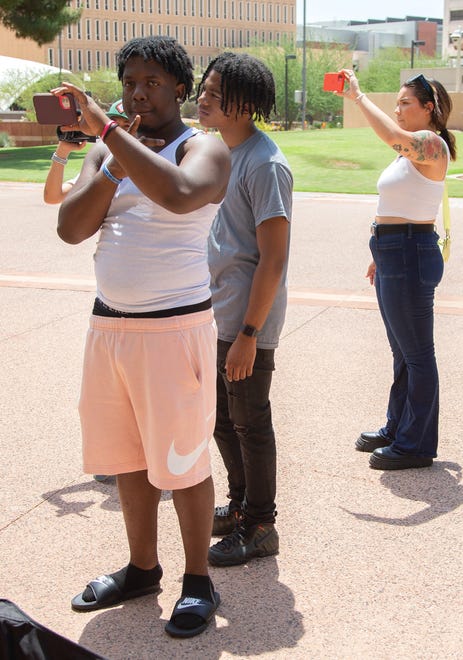 Justin Hervey and Allison DeCoste use their phones to film a news conference at Cesar Chavez Plaza in downtown Phoenix on Aug. 6, 2021. The gathering was a response to the Department of Justice's investigation into the Phoenix Police Department.