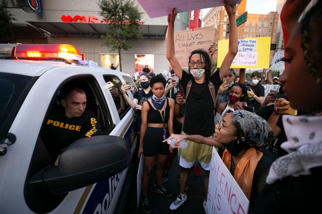 A Phoenix police officer listens to protesters as they gather around a police vehicle at the intersection of Jefferson Street and First Avenue in downtown Phoenix for the eighth day of protests on June 4, 2020, on behalf of George Floyd, Dion Johnson, and others who were killed by police across the country. The protest was held in solidarity with protests across the country against police violence.