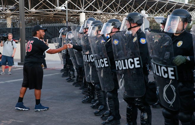 Robert Dossie bumps fists with an officer holding a line outside the Phoenix Police Department in downtown Phoenix on June 1, 2020. People have been demonstrating for George Floyd, killed by police in Minnesota, and Dion Johnson, shot by an Arizona Department of Public Safety officer in Phoenix.