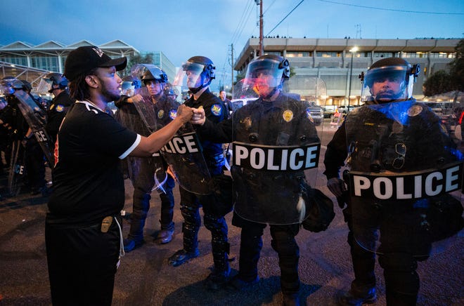 Protester Robert Dossie (left) bumps fists with a Phoenix Police officer in a show of mutual respect after demonstrators peacefully left police headquarters as the 8:00 PM curfew went into effect during a march in response to George Floyd, who died in police custody on May 25, 2020, in Minneapolis, Phoenix, June 1, 2020.