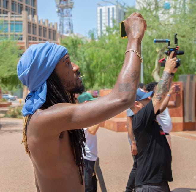 A man films a news conference at Cesar Chavez Plaza in downtown Phoenix on Aug. 6, 2021. The gathering was a response to the Department of Justice's investigation into the Phoenix Police Department.