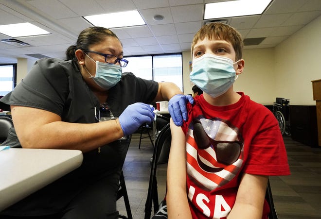 Logan Hute, 9, receives his COVID-19 vaccine from medical assistant Mary Rojas at Native Health Central clinic in Phoenix on Nov. 5, 2021.