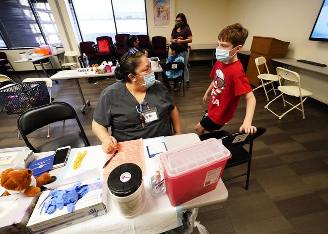 Logan Hute, 9, steps up to receive his COVID-19 vaccine from medical assistant Mary Rojas at Native Health Central clinic in Phoenix on Nov. 5, 2021.
