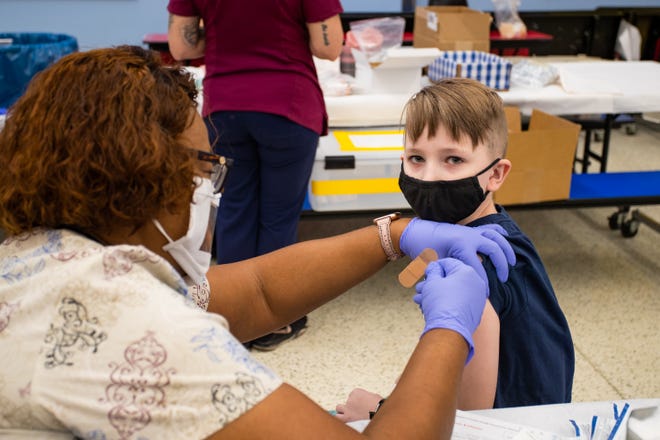 Behrett Brastad, right, receives COVID-19 vaccination from Zelma Washington at John F. Long Elementary in Phoenix, Ariz. on Nov. 5, 2021.