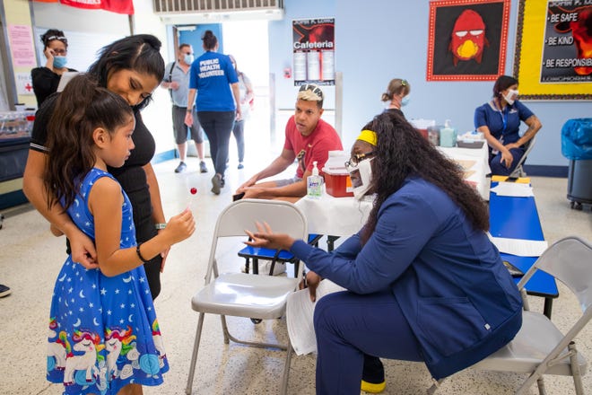 Isabella Huston, 7, deals with nerves before receiving a COVID-19 Vaccination at John F. Long Elementary with her mom, Jessica Palacios, and Shay Johnson in Phoenix Ariz. on Nov. 5, 2021.