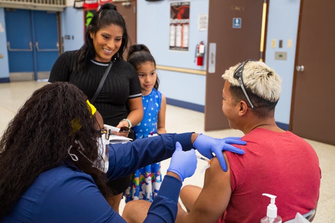 Jessica Palacios, and daughter, Isabella Huston watch Isabella's father, Brad Huston, receive his first COVID-19 vaccination at John F. Long Elementary in Phoenix, Ariz. on Nov. 5, 2021.