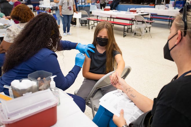 Ellie Murray, 9, receives a COVID-19 vaccination at John F. Long Elementary in Phoenix, Ariz. from Shay Johnson as Samantha Murray holds Ellie's hand on Nov. 5, 2021.