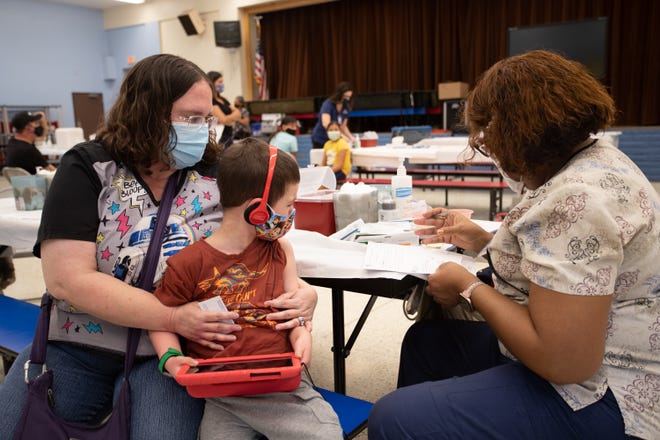 David Courter, 5, in line to receive a COVID-19 vaccination at John F. Long Elementary with Jennifer Courter (left) and Zelma Washington in Phoenix, Ariz. on Nov. 5, 2021.