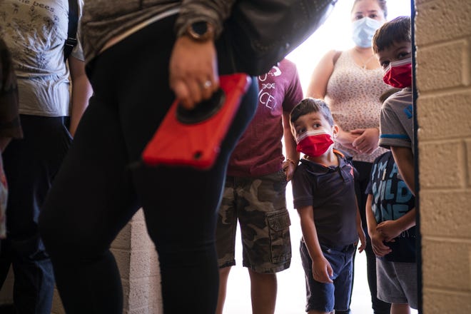 Emiliano Moctezuma, 2, center, looks into the vaccination facility before his older brothers get their first dose of the COVID-19 vaccine on Saturday, Nov. 6, 2021, at Carl Hayden Community High School in Phoenix.