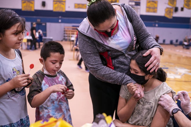 MaKayla Griego, 10, right, holds onto her mother Veronica, top, as her brother AJ, 5, center, and sister Melinda, 8, left, watch as their sister receives her first dose of the COVID-19 vaccine on Saturday, Nov. 6, 2021, at Carl Hayden Community High School in Phoenix.