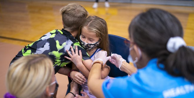 Hazel Talcott (center), 5, is comforted by her brother Huxley, 8, and mother, Chelsie, after receiving her first dose of the COVID-19 vaccine on Nov. 6, 2021, at Carl Hayden Community High School in Phoenix.