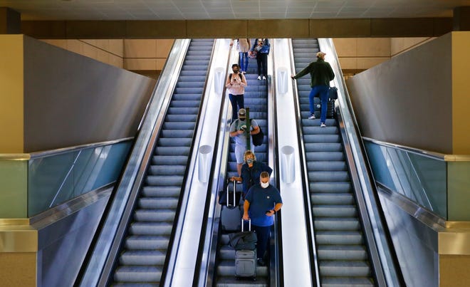Travelers make their way down and up the escalator from the gates to baggage claim at Phoenix Sky Harbor International Airport on Nov. 23, 2021, in Phoenix.