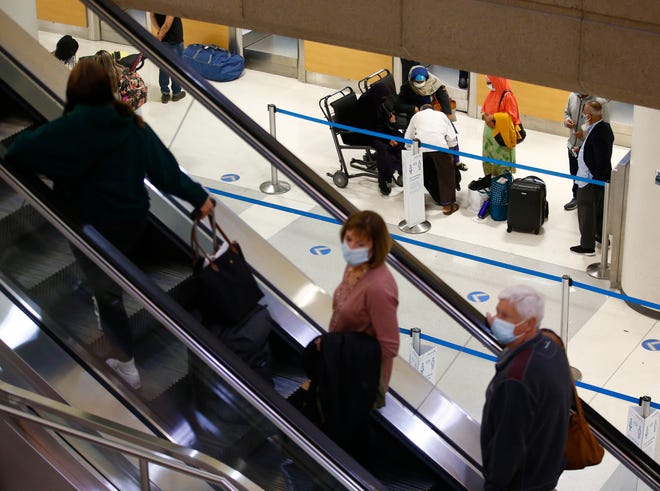 Travelers make their way down and up the escalator from the gates to baggage claim at Phoenix Sky Harbor International Airport on Nov. 23, 2021, in Phoenix.