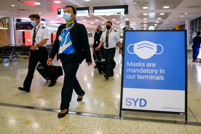 Una tripulación de vuelo camina por la terminal del aeropuerto de Sydney. Las autoridades australianas informaron de que dos viajeros llegados a Sídney procedentes de África se convirtieron en los primeros del país en dar positivo en la nueva variante del COVID, el omicron.