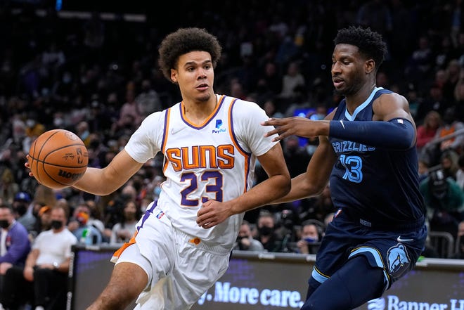 Phoenix Suns forward Cameron Johnson (23) drives on Memphis Grizzlies forward Jaren Jackson Jr. during the first half of an NBA basketball game Monday, Dec. 27, 2021, in Phoenix.