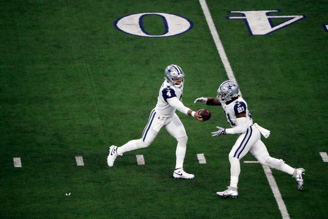 Dallas Cowboys quarterback Dak Prescott (4) hands the ball off to running back Ezekiel Elliott (21) during the first half of an NFL football game against the Arizona Cardinals Sunday, Jan. 2, 2022, in Arlington, Texas. (AP Photo/Roger Steinman)
