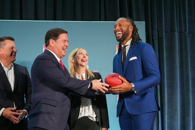 Doug Ducey, governor of Arizona, left, hands off a football to Larry Fitzgerald, former Cardinals wide receiver and executive chairperson of the Arizona Super Bowl host committee, right, as Michael Bidwill, owner of the Arizona Cardinals, left, and Jay Parry, Arizona Super Bowl Host Committee CEO, center, watch during the official Super Bowl Host Committee handoff press conference at the Los Angeles Convention Center on Monday, Feb. 14, 2022, in Los Angeles.