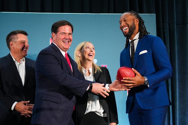 Doug Ducey, governor of Arizona (left), hands off a football to Larry Fitzgerald, former Cardinals wide receiver and executive chairperson of the Arizona Super Bowl host committee (right), as Michael Bidwill, owner of the Arizona Cardinals (far left), and Jay Parry, Arizona Super Bowl Host Committee CEO (center), look on during the official Super Bowl Host Committee hand off press conference at the Los Angeles Convention Center on Monday, Feb. 14, 2022, in Los Angeles.