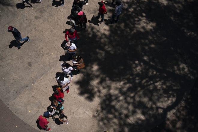 Migrants stand in line to speak with volunteers during a vigil near the DeConcini port of entry for the continuation of Title 42 on May 23, 2022, in Nogales, Mexico. A federal judge in Louisiana ruled that Title 42, a Trump administration era public health order, must stay in place; making it difficult for migrants in Mexico to seek asylum to the U.S.