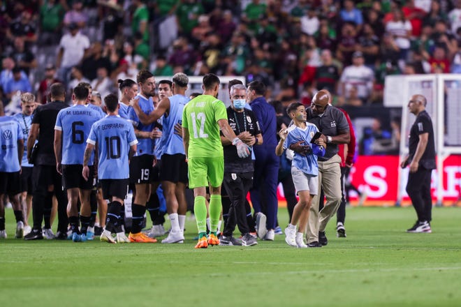 Un aficionado uruguayo es llevado por la seguridad despu é s de que lograra entrar al campo para saludar a los jugadores de su equipo despu é s del segundo tiempo entre M é xico y Uruguay en el State Farm Stadium el jueves 2 de junio de 2022, en Glendale.