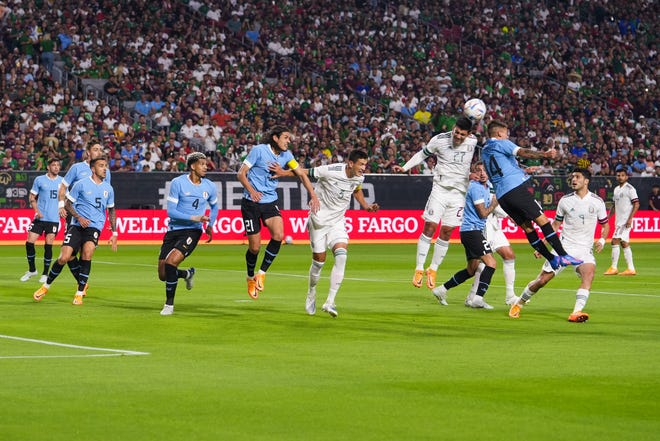 El defensa de M é xico Jes ú s Angulo (27), a la derecha, cabecea el bal ó n mientras es vigilado por el centrocampista de Uruguay Lucas Torreira (14), a la derecha, durante el primer tiempo entre M é xico y Uruguay en el State Farm Stadium el jueves 2 de junio de 2022, en Glendale.