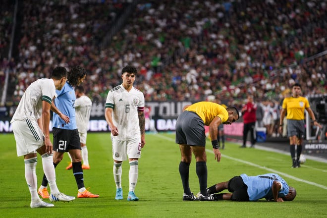 El centrocampista uruguayo Nicol á s de la Cruz (7), a la derecha, cae tras una falta durante el segundo tiempo entre M é xico y Uruguay en el State Farm Stadium el jueves 2 de junio de 2022, en Glendale.