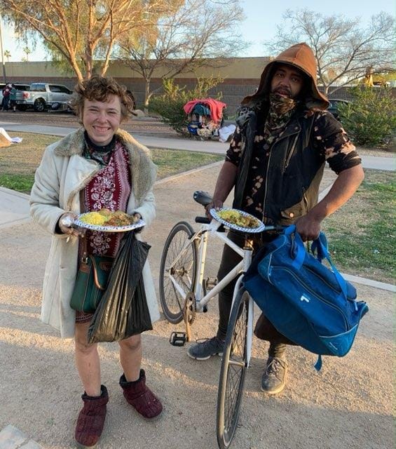 Sean Bickings, right, and Susanna Smith, left, pose for a picture with meal plates at Jaycee Park in Tempe during an event organized by Aris Foundation.